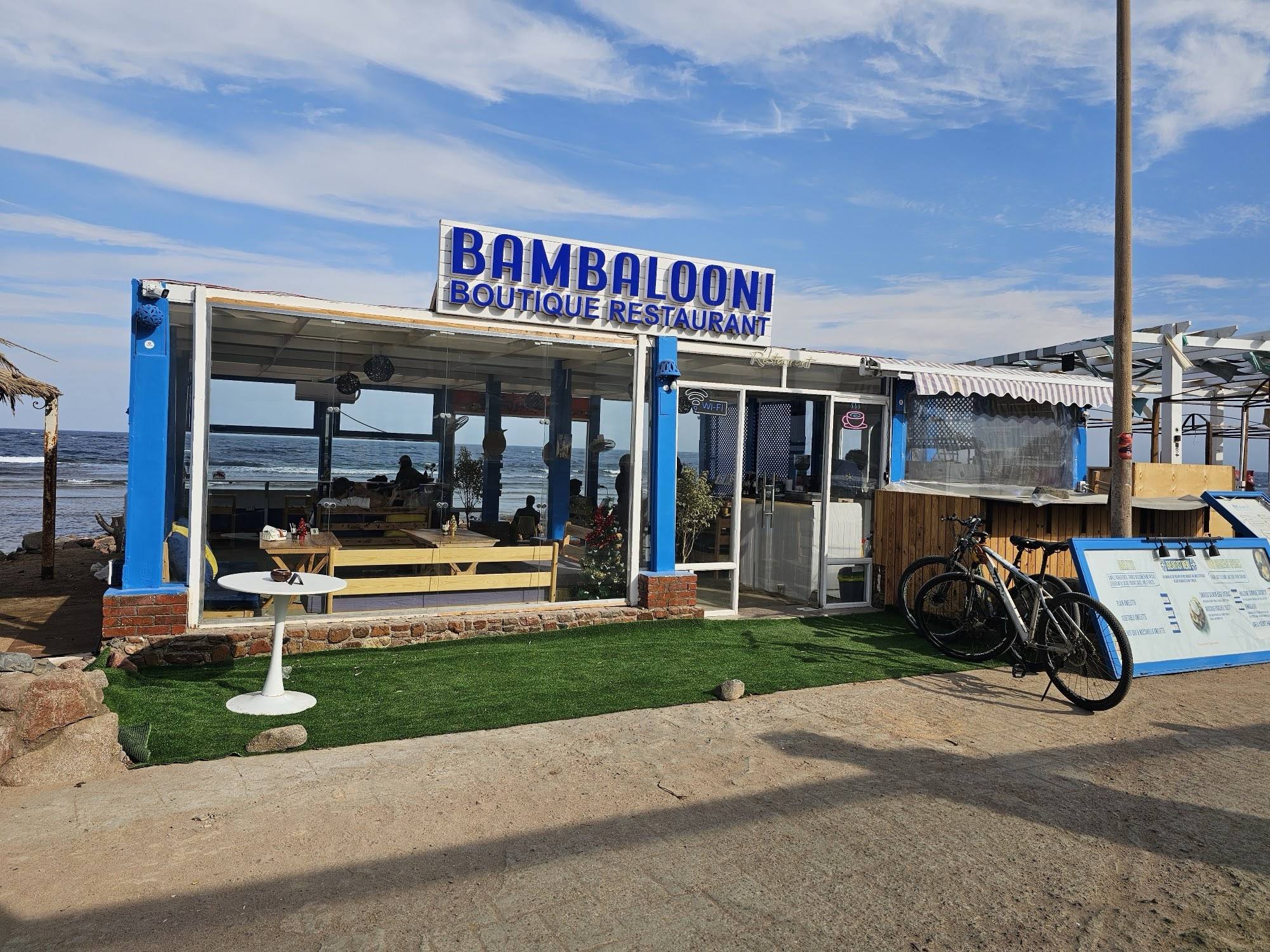 Bambalooni Boutique Restaurant on the Dahab seafront, with its blue sign and the Red Sea behind the glass walls
